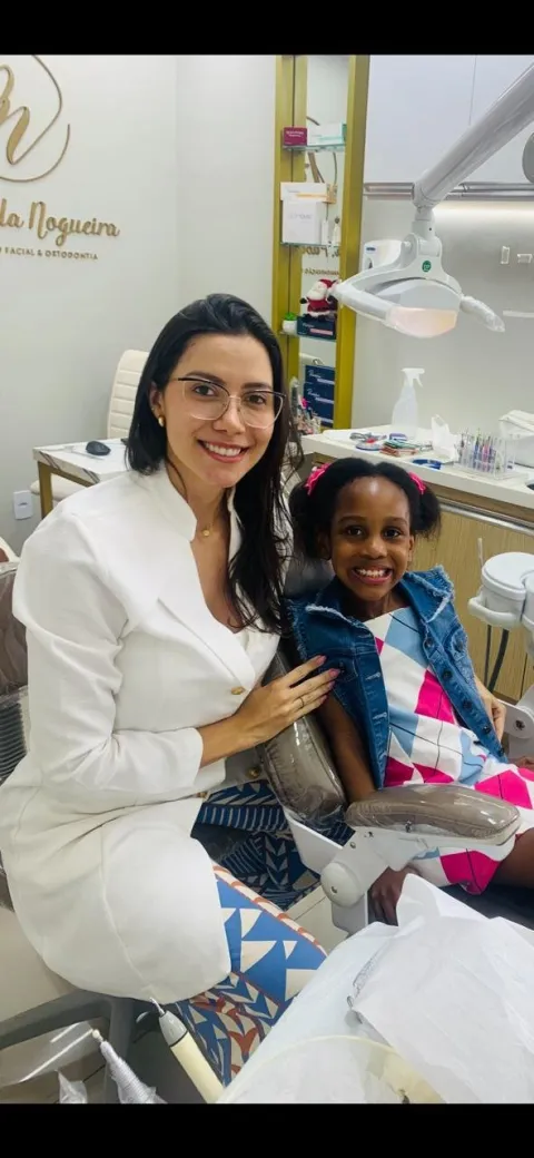 Dra. Paola sorrindo ao lado de uma paciente